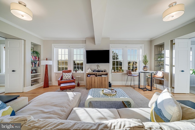 living room featuring a wealth of natural light, built in features, beamed ceiling, and light hardwood / wood-style flooring