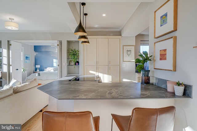 kitchen featuring a kitchen bar, kitchen peninsula, hanging light fixtures, light wood-type flooring, and white cabinets