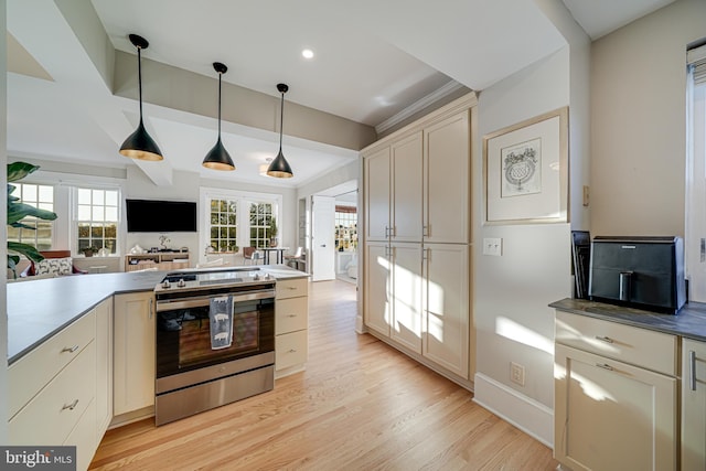 kitchen featuring light wood-type flooring, cream cabinetry, stainless steel range, and decorative light fixtures