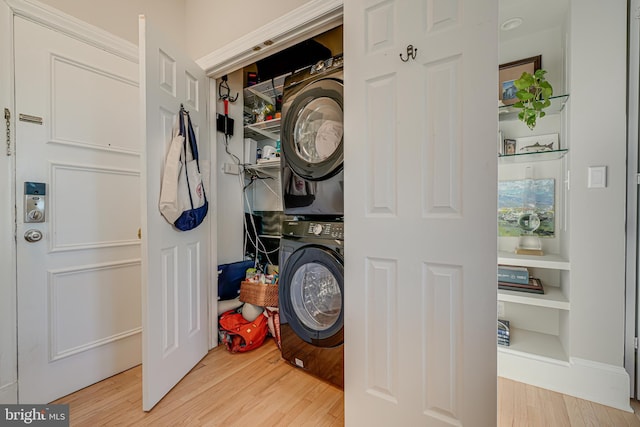 clothes washing area with wood-type flooring and stacked washer and clothes dryer