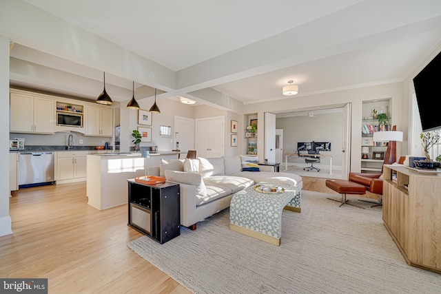 living room featuring beamed ceiling, light hardwood / wood-style floors, and sink