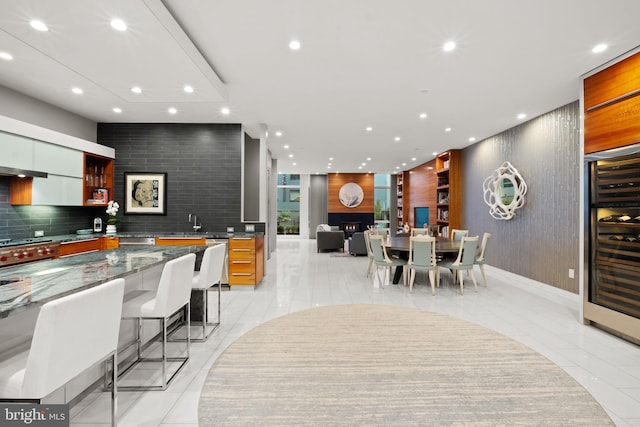 kitchen featuring decorative backsplash, a breakfast bar, light tile patterned floors, dark stone countertops, and wine cooler