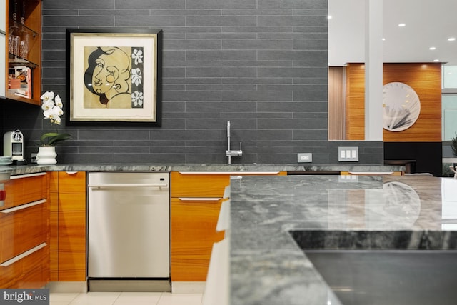 kitchen with dark stone counters, decorative backsplash, light tile patterned flooring, and stainless steel dishwasher