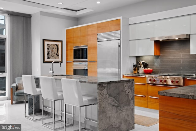 kitchen with white cabinetry, sink, a kitchen breakfast bar, backsplash, and appliances with stainless steel finishes