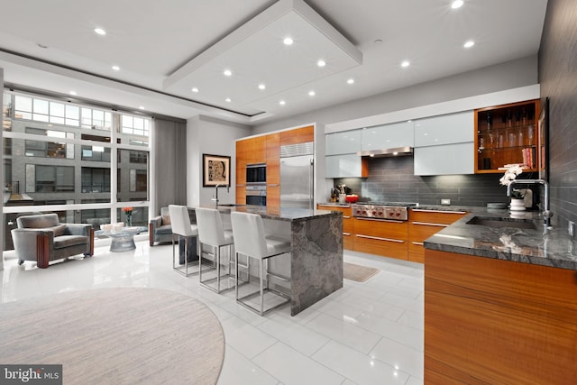 kitchen featuring white cabinetry, sink, a kitchen breakfast bar, backsplash, and appliances with stainless steel finishes