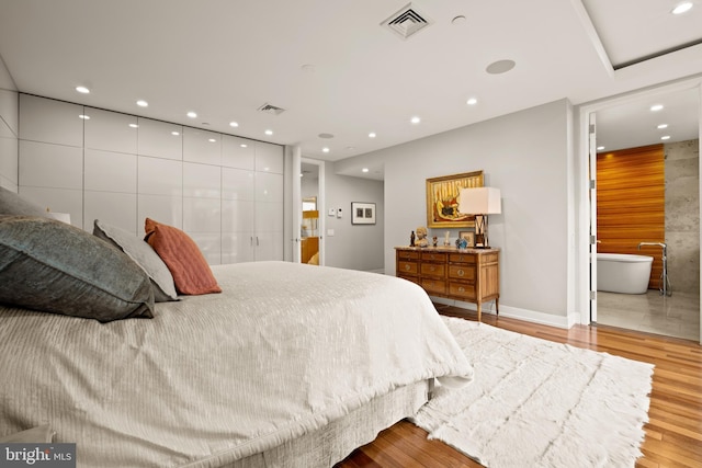 bedroom with ensuite bathroom and light wood-type flooring