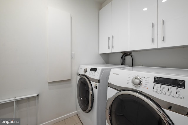 clothes washing area with light tile patterned floors, cabinets, and independent washer and dryer