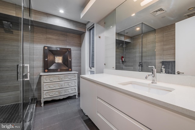 bathroom with walk in shower, vanity, tile patterned floors, and tile walls