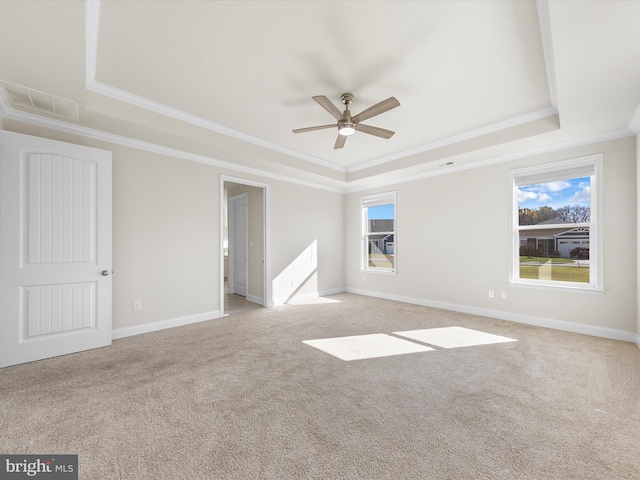 carpeted spare room featuring ceiling fan, a tray ceiling, crown molding, and plenty of natural light