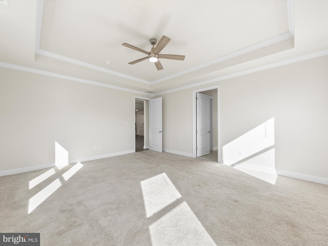 unfurnished room featuring a tray ceiling, ceiling fan, light colored carpet, and ornamental molding