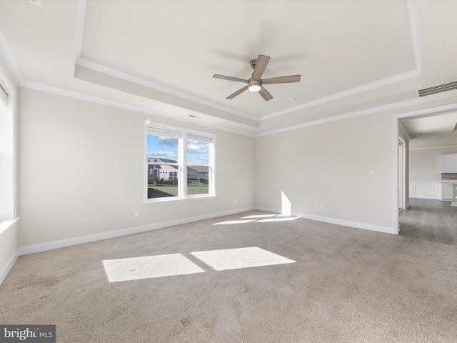 carpeted empty room featuring a raised ceiling, crown molding, and ceiling fan