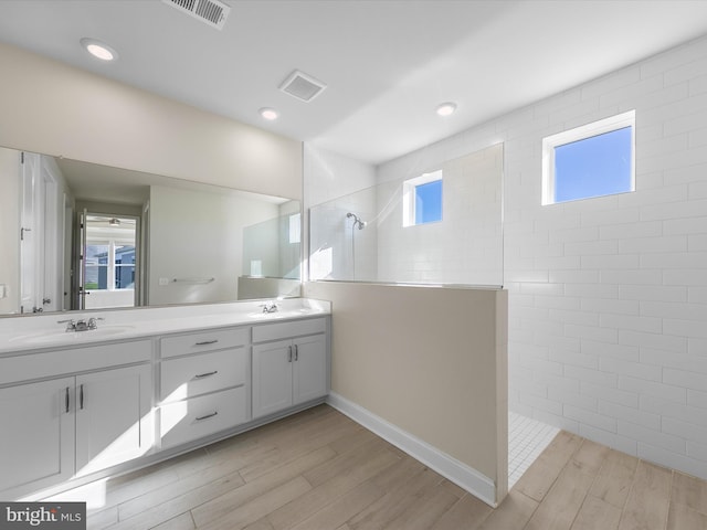 bathroom with hardwood / wood-style floors, vanity, and tiled shower