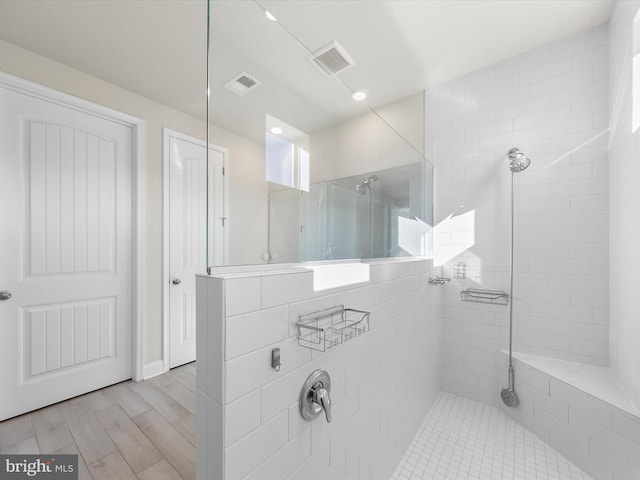 bathroom with tiled shower and hardwood / wood-style flooring