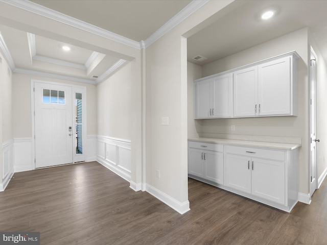 foyer entrance featuring a raised ceiling, crown molding, and dark wood-type flooring