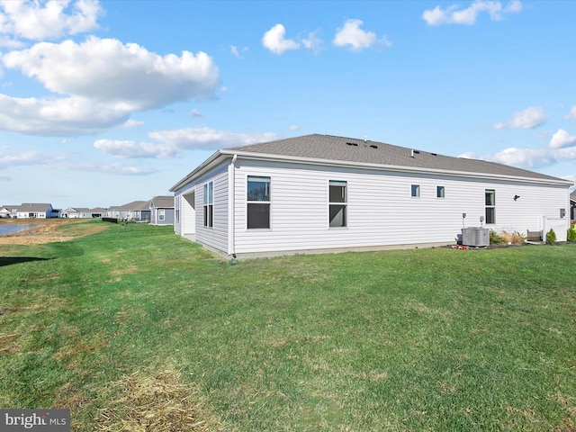 rear view of property featuring cooling unit and a lawn