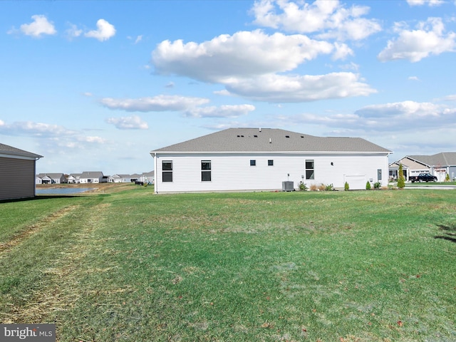 rear view of house featuring a lawn and central AC unit