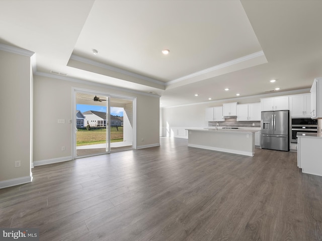 unfurnished living room featuring a tray ceiling, ceiling fan, dark wood-type flooring, and ornamental molding