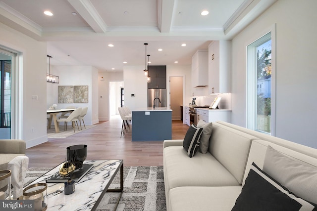 living room with crown molding, light hardwood / wood-style flooring, beamed ceiling, and a chandelier