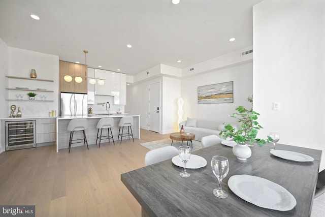 living room featuring wine cooler, light wood-type flooring, and sink