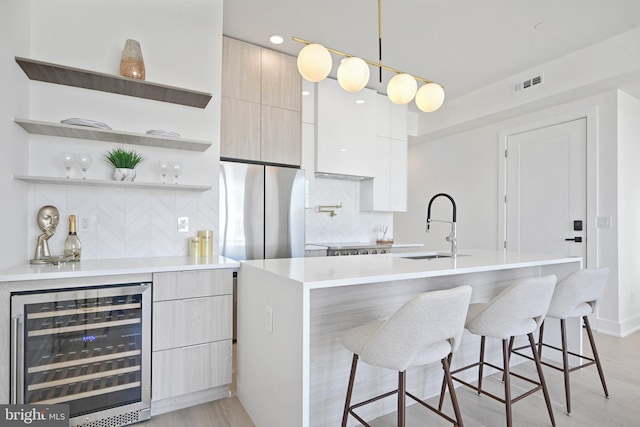 kitchen with stainless steel fridge, light hardwood / wood-style flooring, a breakfast bar, and wine cooler