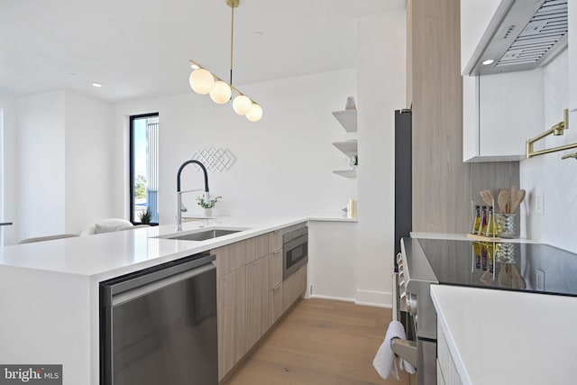 kitchen featuring sink, kitchen peninsula, pendant lighting, light wood-type flooring, and dishwasher