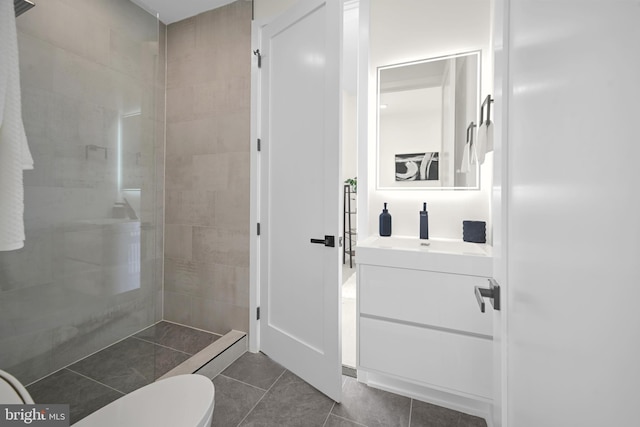 bathroom featuring toilet, vanity, tile patterned floors, and tiled shower