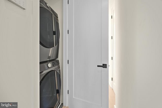 clothes washing area with stacked washer and clothes dryer and a barn door