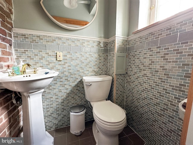 bathroom with tile patterned floors, toilet, and tile walls