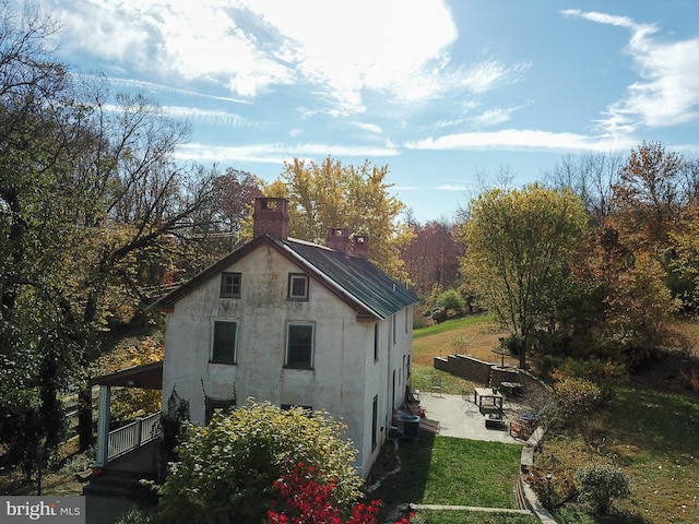 view of side of property featuring a yard, central AC, and a patio area