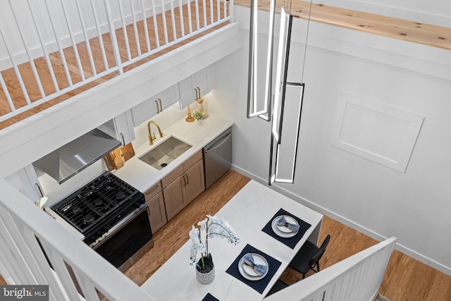 kitchen with stainless steel dishwasher, light hardwood / wood-style floors, sink, and black range oven