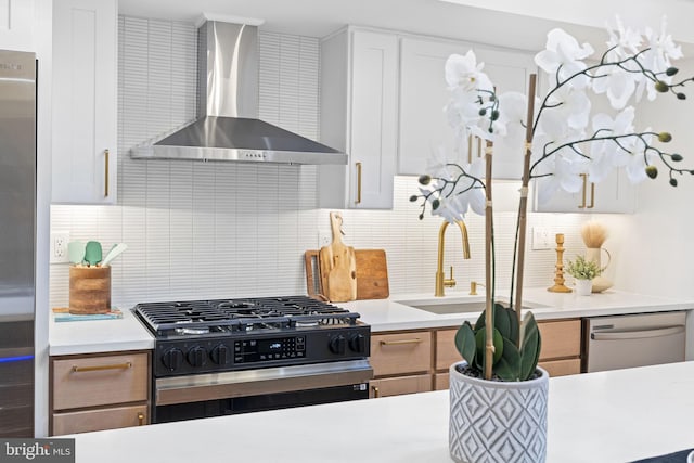 kitchen featuring stainless steel appliances, wall chimney range hood, white cabinets, and backsplash