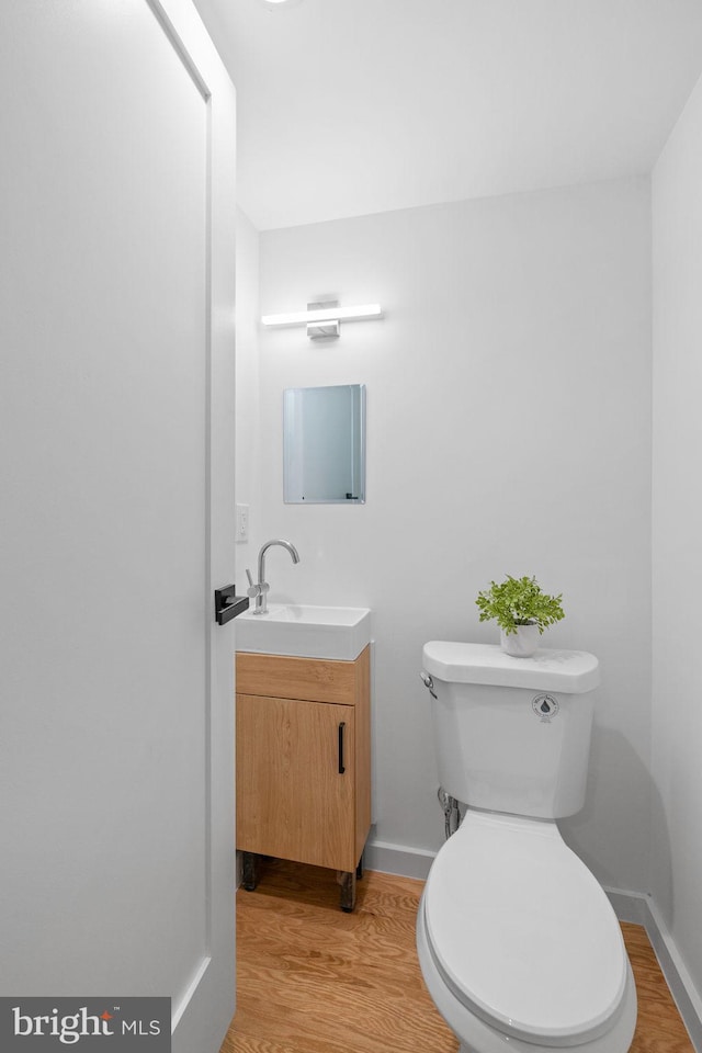 bathroom with hardwood / wood-style flooring, vanity, and toilet