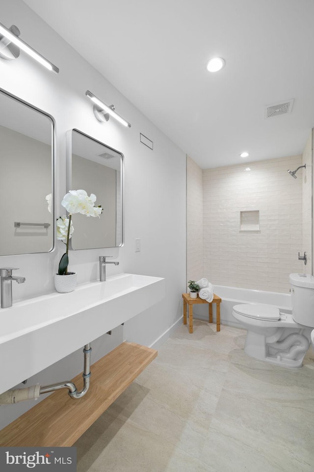 bathroom featuring toilet and tiled shower / bath