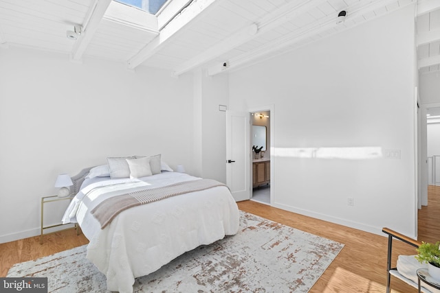 bedroom featuring wooden ceiling, beamed ceiling, light wood-type flooring, and a skylight