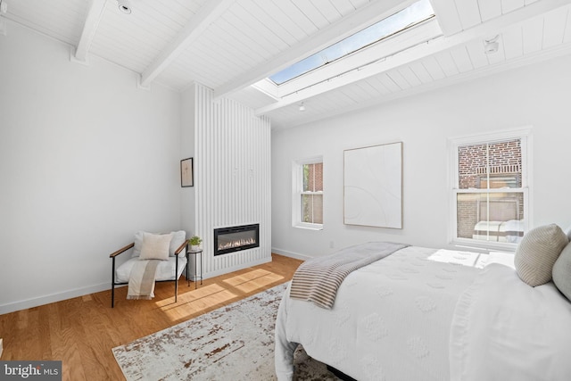 bedroom with hardwood / wood-style flooring, multiple windows, a skylight, and beam ceiling