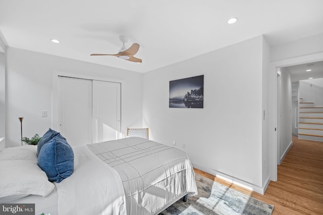 bedroom with light hardwood / wood-style floors, ceiling fan, and a closet