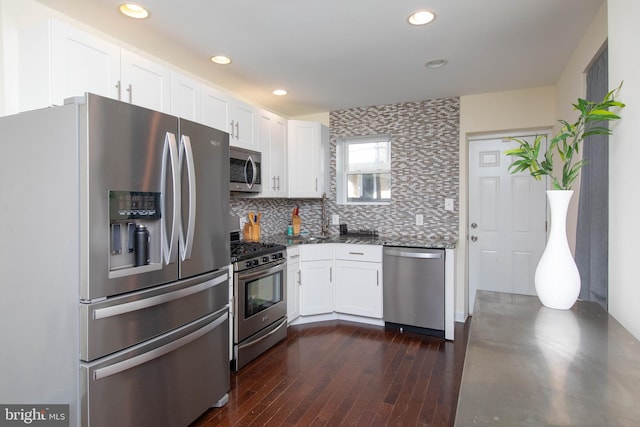 kitchen with decorative backsplash, white cabinets, stainless steel appliances, and dark hardwood / wood-style floors