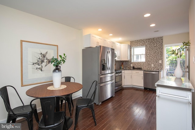 kitchen with decorative backsplash, white cabinetry, dark wood-type flooring, and appliances with stainless steel finishes