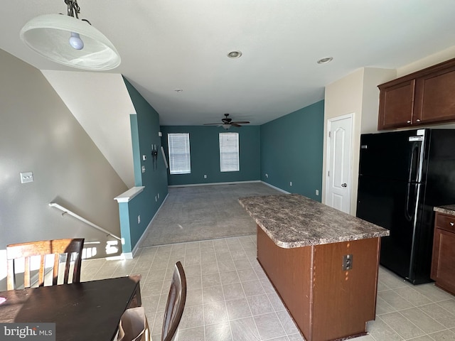 kitchen featuring black fridge, a center island, ceiling fan, and light carpet