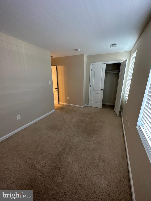 unfurnished bedroom featuring carpet flooring and a closet