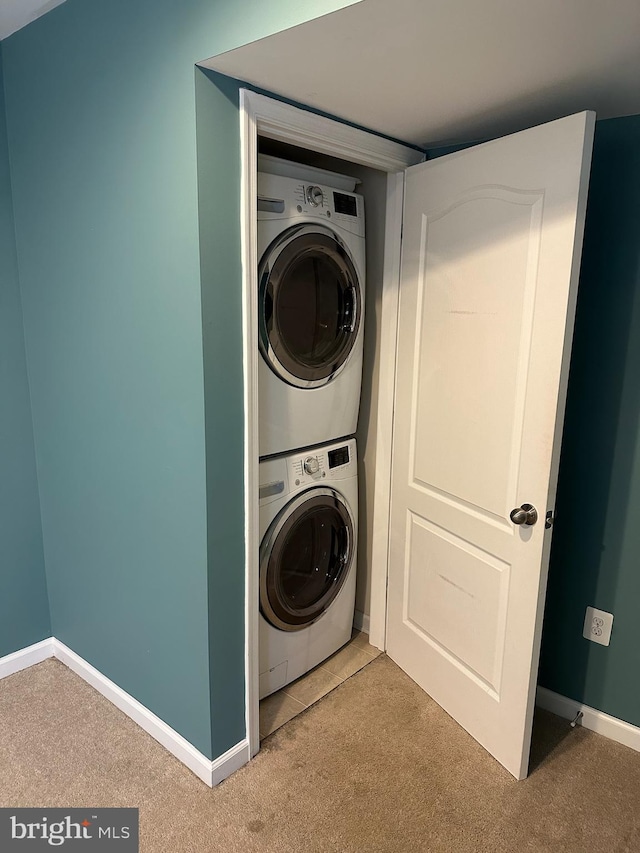 clothes washing area featuring carpet floors and stacked washer and dryer