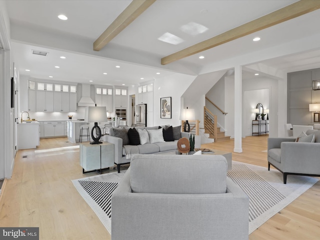 living room with beamed ceiling, light hardwood / wood-style floors, and sink