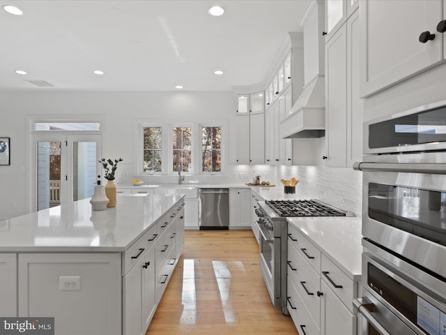 kitchen featuring appliances with stainless steel finishes, light hardwood / wood-style flooring, white cabinetry, and a kitchen island