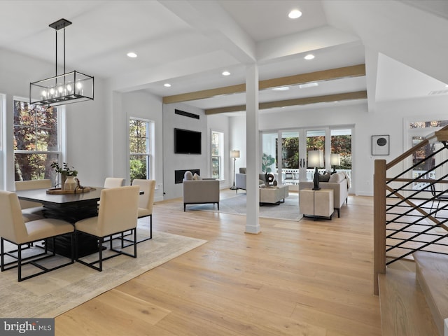 dining room with beamed ceiling, light hardwood / wood-style floors, a wealth of natural light, and an inviting chandelier