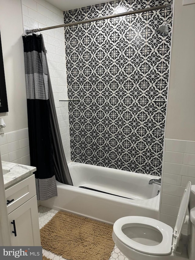 full bathroom featuring shower / tub combo with curtain, vanity, tile patterned floors, toilet, and tile walls