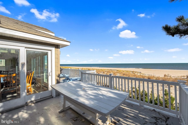 wooden terrace featuring a water view and a beach view