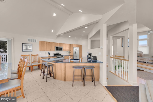 kitchen with appliances with stainless steel finishes, sink, light tile patterned floors, lofted ceiling with beams, and a breakfast bar area