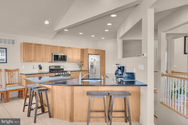 kitchen with a breakfast bar, sink, light tile patterned floors, kitchen peninsula, and stainless steel appliances