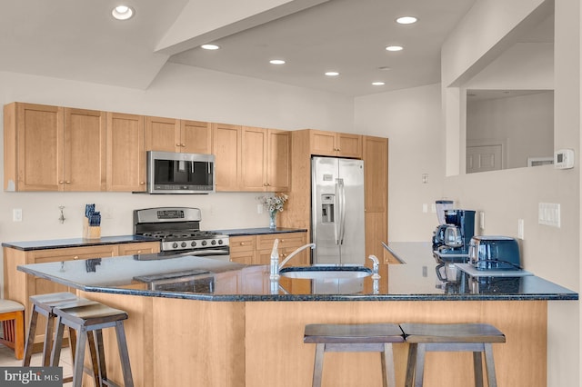 kitchen with kitchen peninsula, sink, appliances with stainless steel finishes, and a breakfast bar area