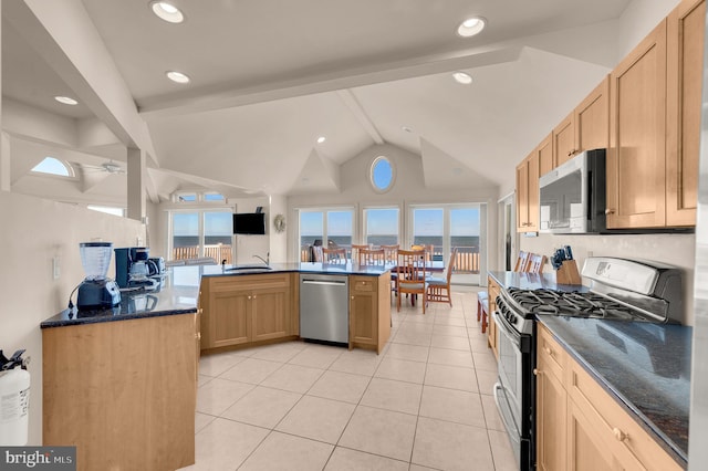 kitchen featuring plenty of natural light, lofted ceiling with beams, stainless steel appliances, and dark stone counters